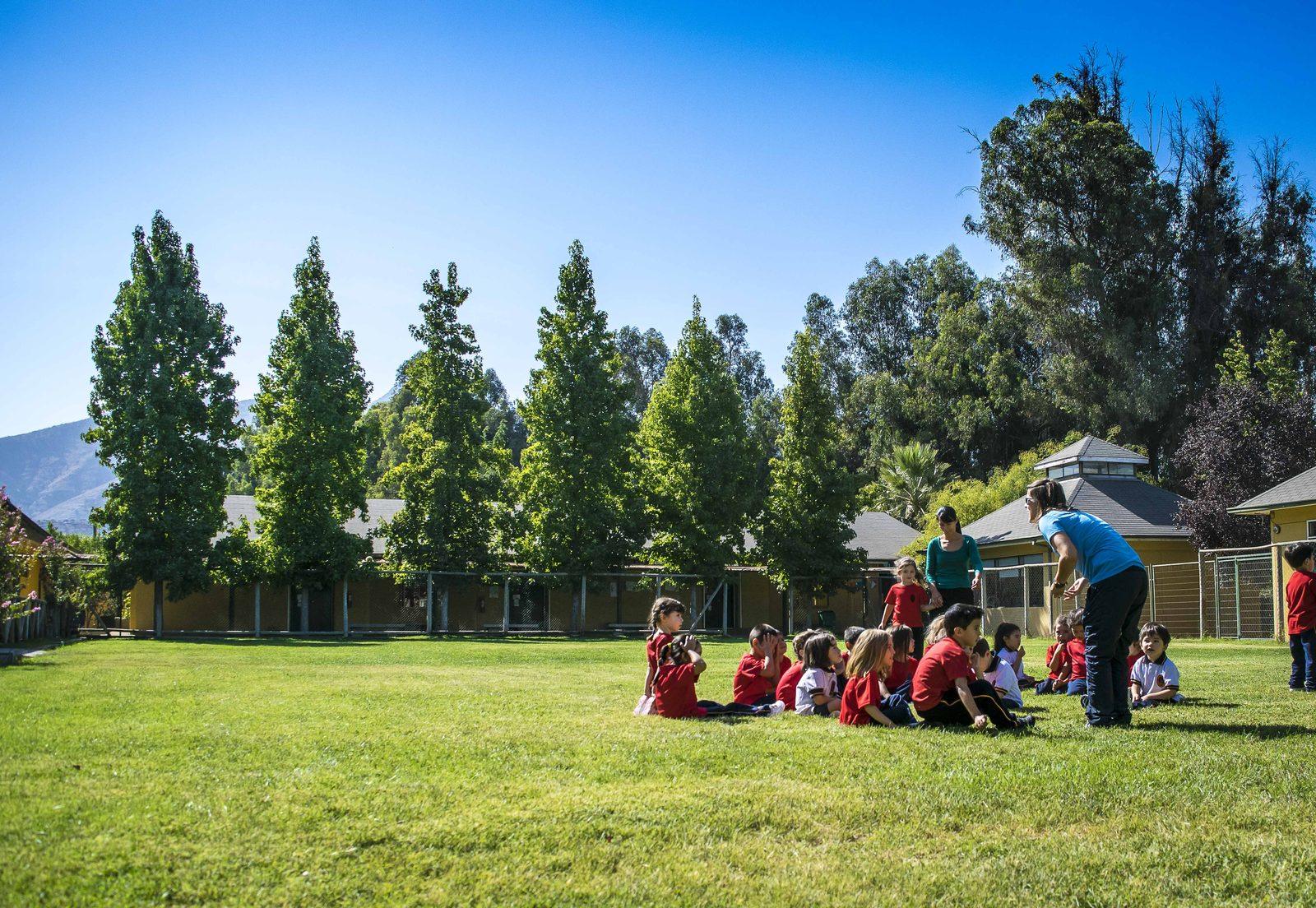 Campus del Colegio Campanario en Alto Jahuel, con alumnos en el pasto entre árboles